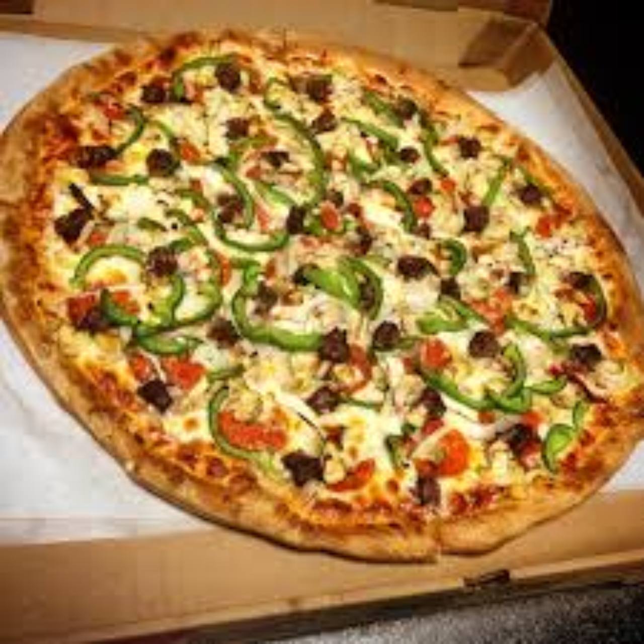 Specialty pizza with peppers, mushrooms, tomatoes, and meat.